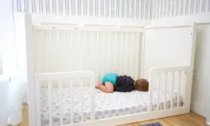 A baby sleeps on a floor bed with an elephant print sheet. This setup raises questions about whether floor beds are safe for babies.