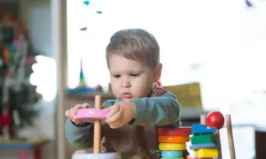 A toddler explores stacking toys, demonstrating early understanding of Montessori schemas.