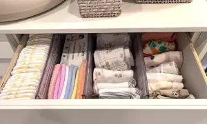 Drawer neatly organized with diapers, wipes, colorful washcloths, and folded baby clothes. A perfect example of how to organize baby stuff efficiently.