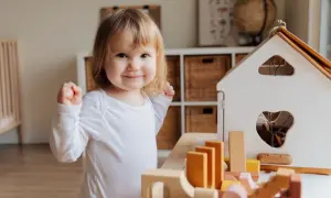 A happy toddler plays with wooden blocks, a perfect scene for learning for 1 year olds.