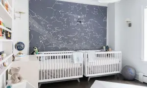 Two white cribs in a nursery with a constellation mural. This is a perfect example of baby boys nursery designs, inspiring dreams of the stars.