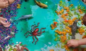 Ocean-themed sensory bin with toy sea creatures, colorful pebbles, and pasta provides engaging sensory activities for 1 year olds.