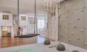 A child's indoor adventure zone with a climbing wall, net, and swing, embodying a Montessori aesthetic.
