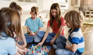 Five children enjoy a board game together, a perfect example of fun things to do with siblings.