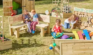 Children explore a vibrant Montessori garden, discovering nature's wonders. A bug city invites curiosity, while a planter box bursts with colorful blooms.
