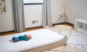 Newborn baby sleeps peacefully on a floor bed.