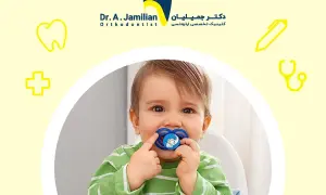 A baby with a pacifier, or binky, in their mouth. The pacifier has a blue elephant design.