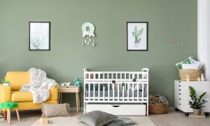 A serene nursery with a yellow armchair, white crib, and cactus art. A perfect nursery painting idea for a calm and natural space.