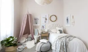 A dreamy baby girls bedroom with a pink canopy, cloud-patterned blanket, and whimsical art.