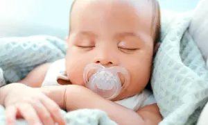 A peaceful newborn sleeps soundly, a pacifier in their mouth. This image shows that newborns do use pacifiers for comfort.