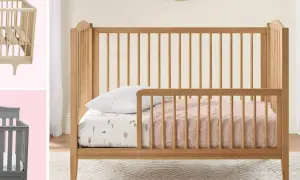 A wooden toddler bed with rails is shown, perfect for what kind of bed should a 2 year old be in. A grey crib is also visible.