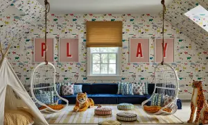 A whimsical playroom set up with animal wallpaper, hanging chairs, a teepee, and plush toys.