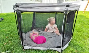 Two toddlers play in a portable playpen, a safe space often called a baby bed.