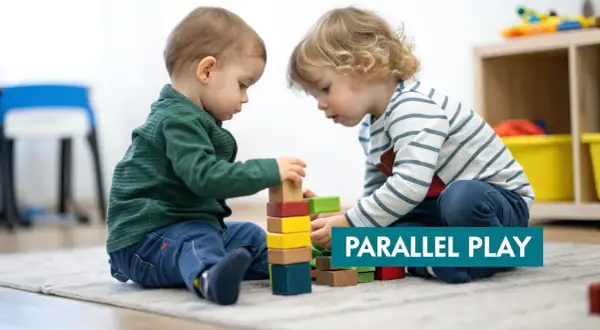 Two toddlers build with blocks, demonstrating the benefits of parallel play.