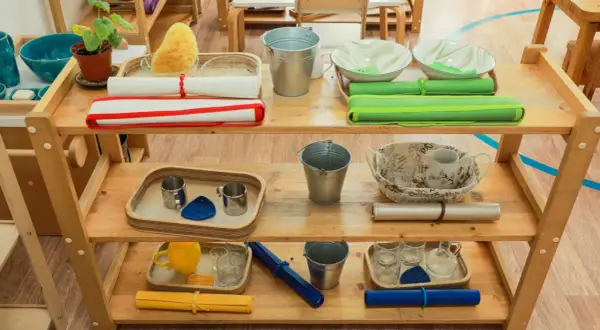 Montessori ideas: Shelves with practical life activities like pouring, washing, and transferring. Includes buckets, bowls, cups, and sponges.