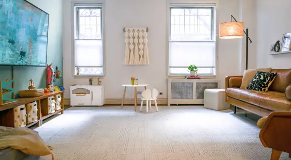 A cozy DIY play room with a brown leather sofa, a small table and chair, and toy storage.