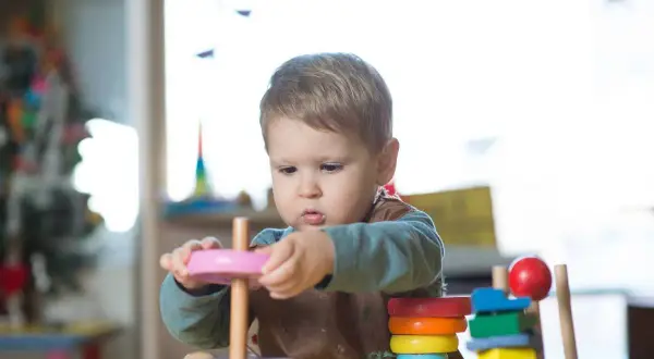 A toddler explores stacking toys, demonstrating early understanding of Montessori schemas.