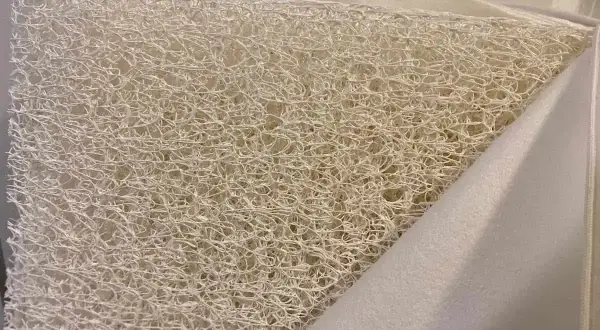 Close-up of a white, airy, woven material, revealing what the Newton mattress is made of: a breathable, open-cell core.