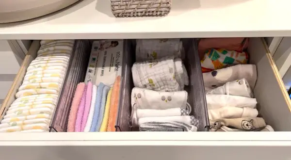 Drawer neatly organized with diapers, wipes, colorful washcloths, and folded baby clothes. A perfect example of how to organize baby stuff efficiently.