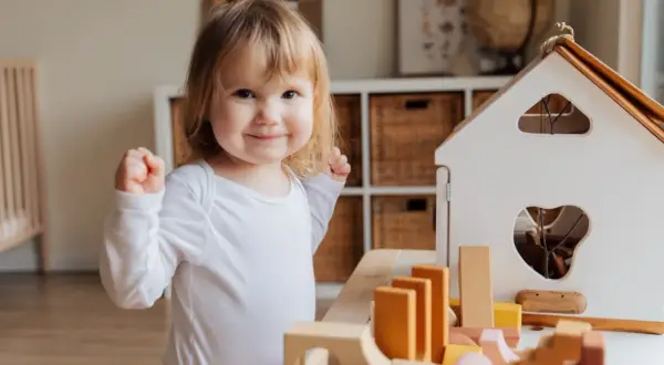 A happy toddler plays with wooden blocks, a perfect scene for learning for 1 year olds.