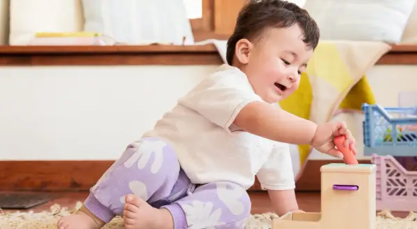 A baby's hand carefully places a toy, showcasing developing baby hand eye coordination.