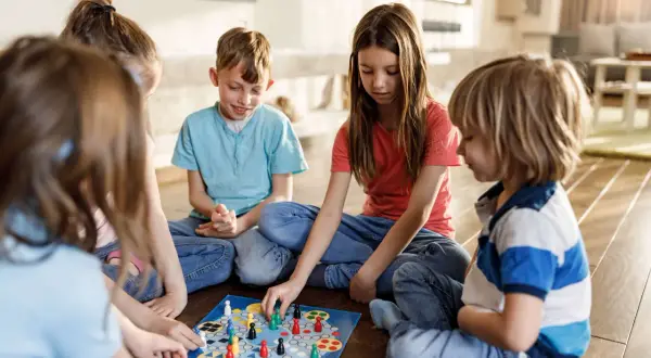 Five children enjoy a board game together, a perfect example of fun things to do with siblings.