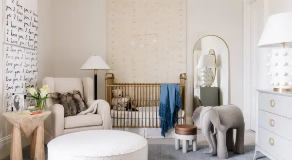A serene nursery with a gold crib, plush armchair, and elephant stool. This space offers fun nursery ideas with its whimsical decor and cozy atmosphere.