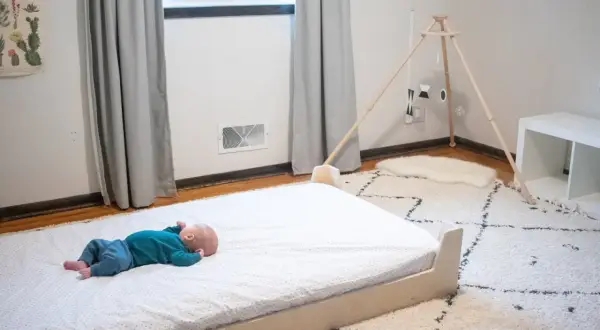Newborn baby sleeps peacefully on a floor bed.