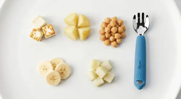 A child can eat with a fork when they master finger foods like these: paneer cubes, potato wedges, chickpeas, banana slices, and melon cubes.