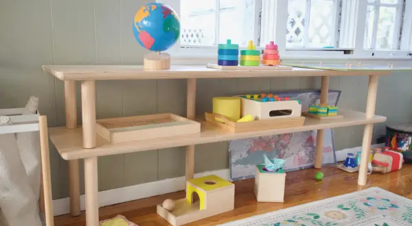 A Montessori shelf for a 1-year-old features a globe, stacking toys, and wooden puzzles, encouraging exploration and learning.