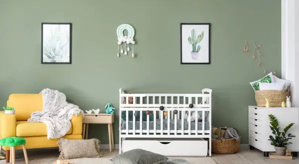 A serene nursery with a yellow armchair, white crib, and cactus art. A perfect nursery painting idea for a calm and natural space.