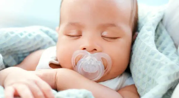 A peaceful newborn sleeps soundly, a pacifier in their mouth. This image shows that newborns do use pacifiers for comfort.