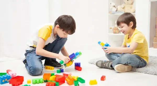Two boys happily build with colorful blocks, showing great ideas for what to play indoors.