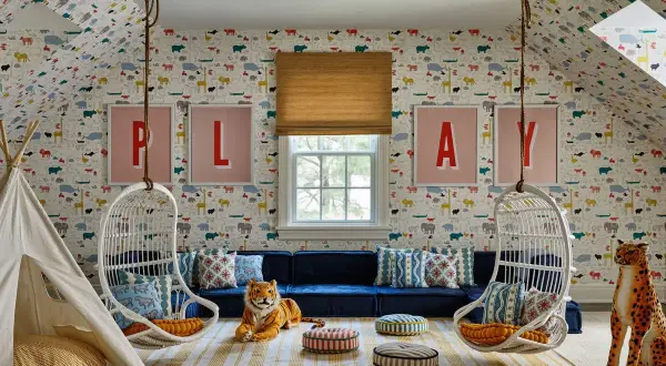 A whimsical playroom set up with animal wallpaper, hanging chairs, a teepee, and plush toys.