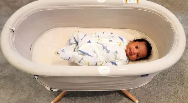 A baby sleeps soundly in a bassinet, a cozy bed for newborns. This bassinet is used for a safe and comfortable sleeping space for infants.