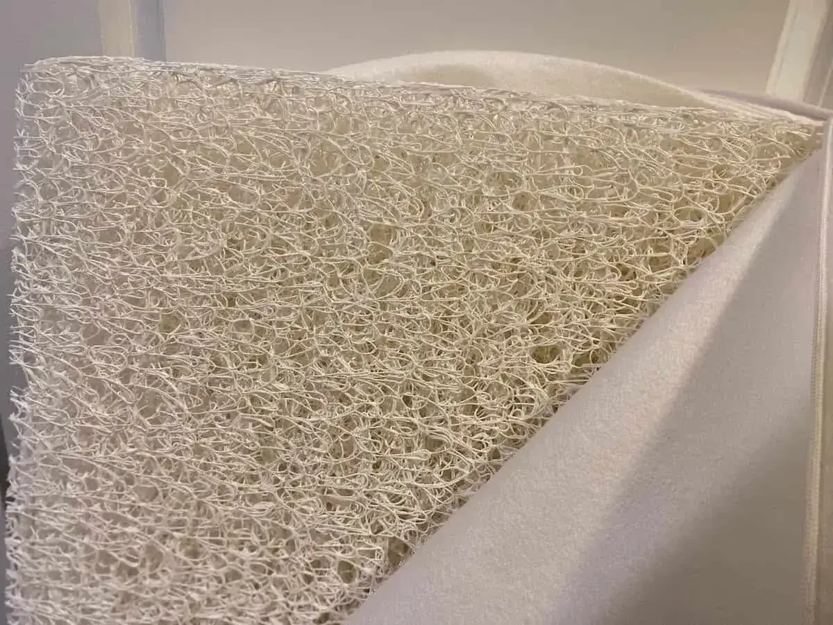 Close-up of a white, airy, woven material, revealing what the Newton mattress is made of: a breathable, open-cell core.