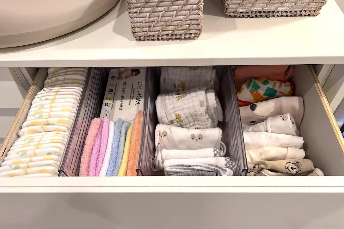 Drawer neatly organized with diapers, wipes, colorful washcloths, and folded baby clothes. A perfect example of how to organize baby stuff efficiently.