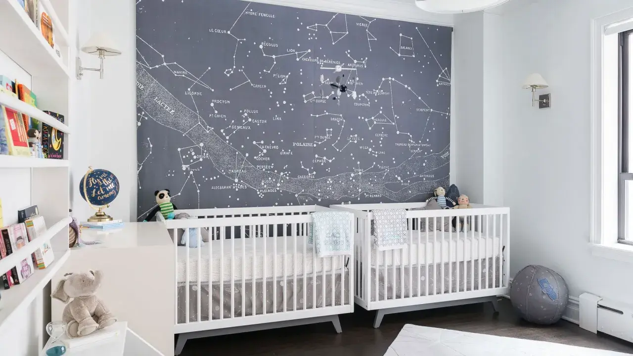 Two white cribs in a nursery with a constellation mural. This is a perfect example of baby boys nursery designs, inspiring dreams of the stars.