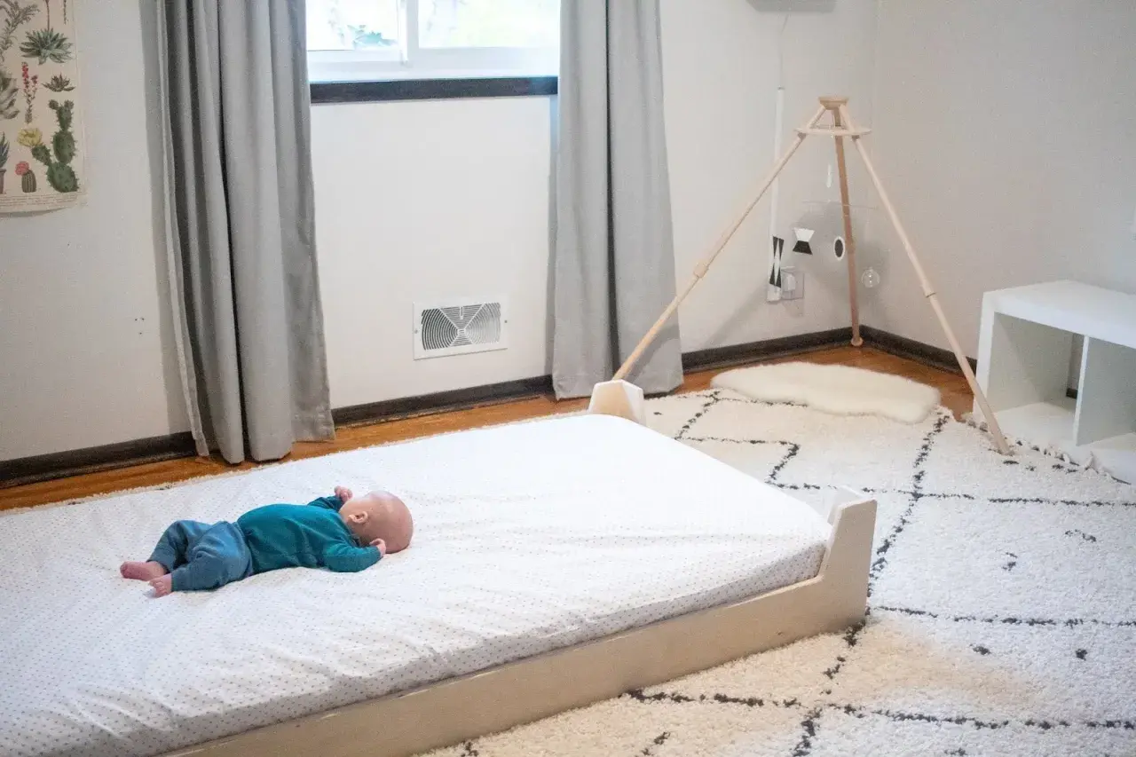Newborn baby sleeps peacefully on a floor bed.