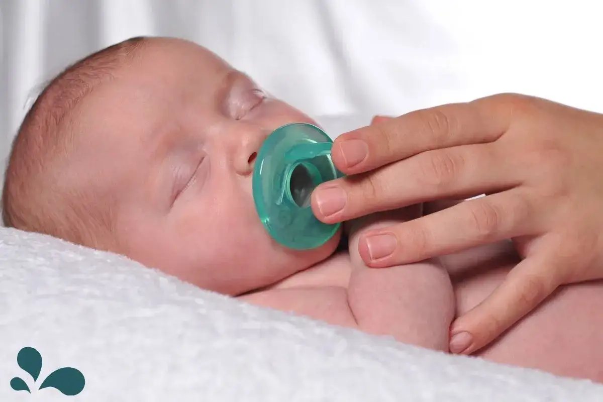 A baby sleeps peacefully with a pacifier, a comforting aid sometimes used after breastfeeding.