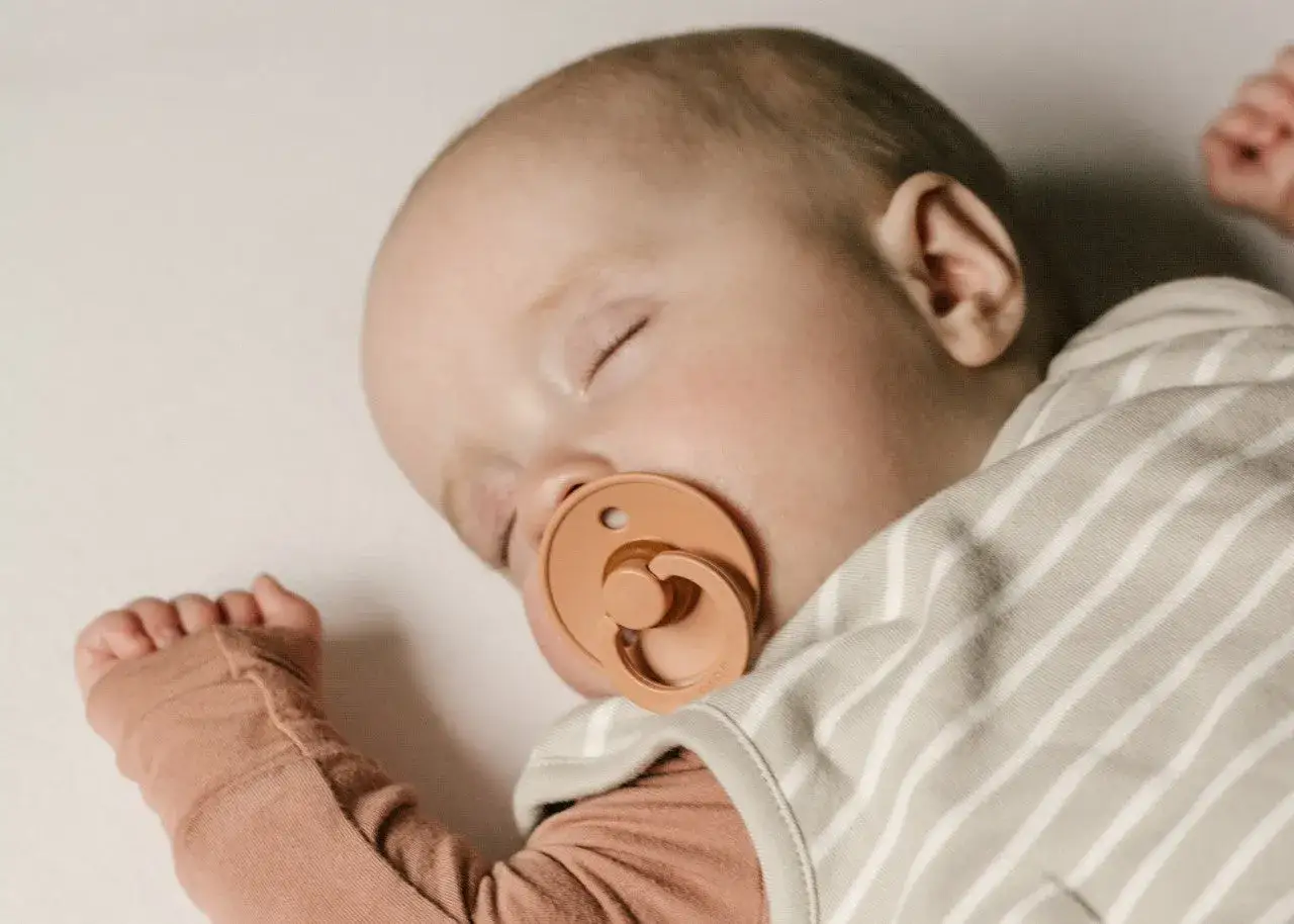 A sleeping newborn with a pacifier in its mouth. This image shows that newborns do use pacifiers for comfort.