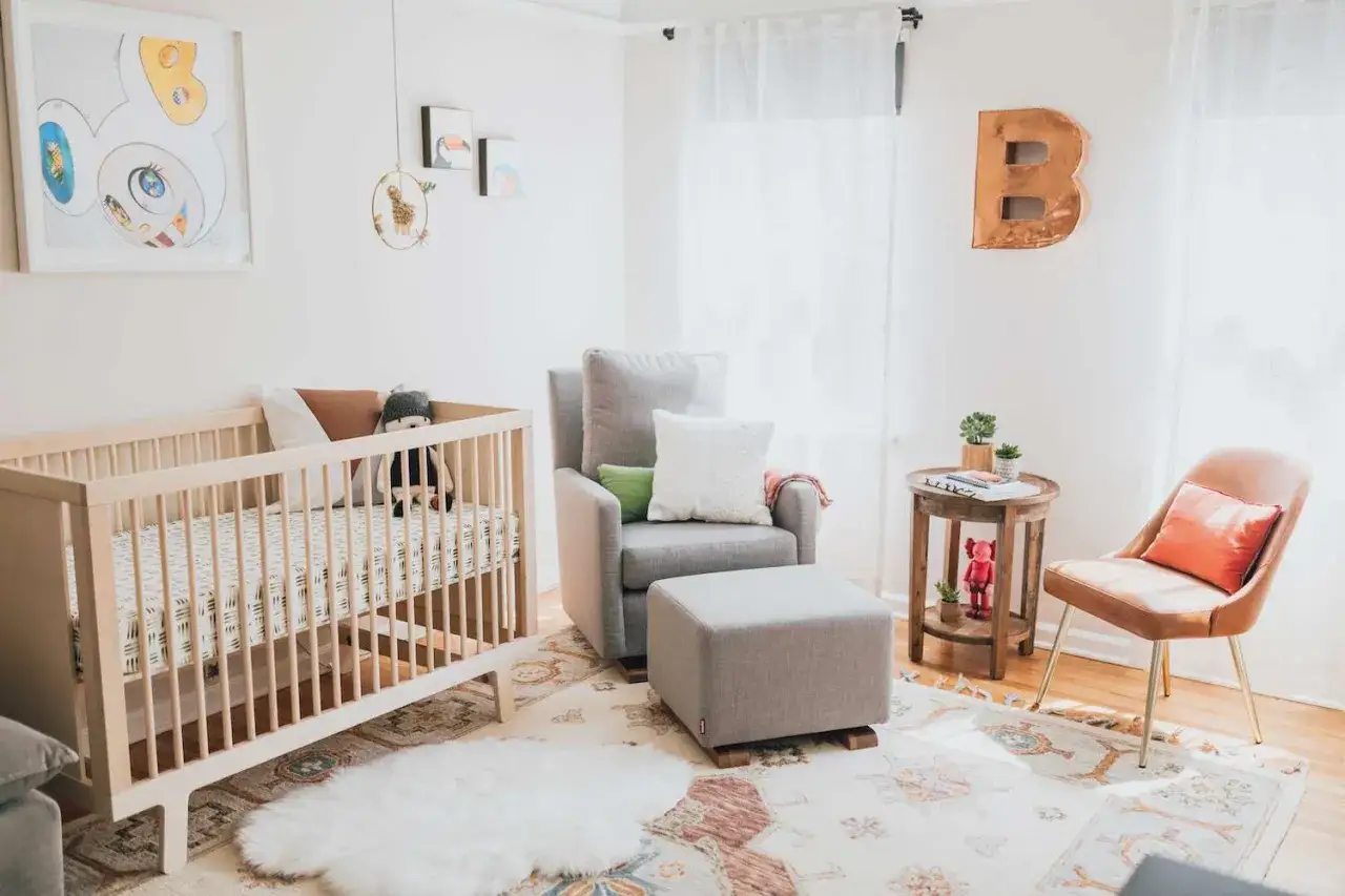A cozy nursery with a wooden crib, plush armchair, and playful wall art. These fun nursery ideas create a welcoming space for a little one.