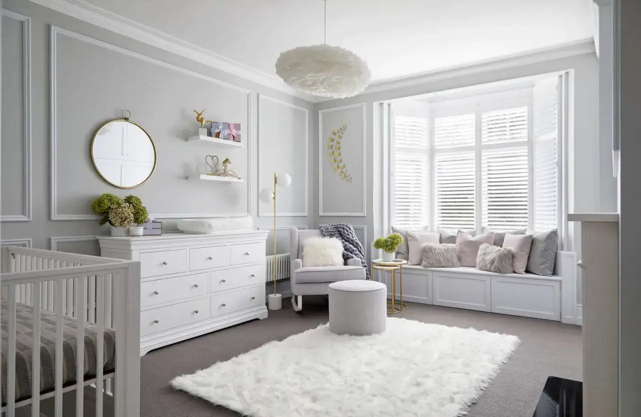 Elegant baby girls room designs feature a white crib, dresser, and plush rug. A cozy window seat with soft pillows completes the serene space.