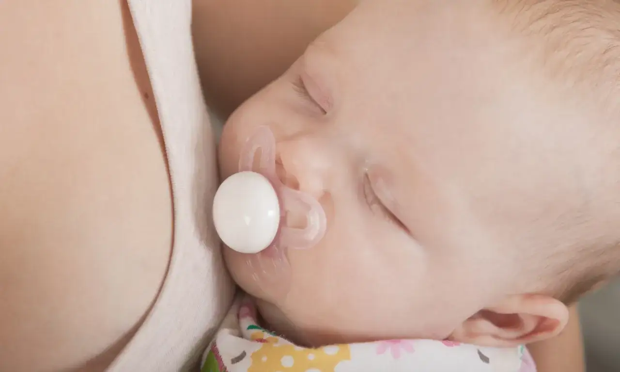 A sleeping baby with a pacifier. Some parents worry about pacifier nipple confusion when introducing a pacifier to a breastfed infant.