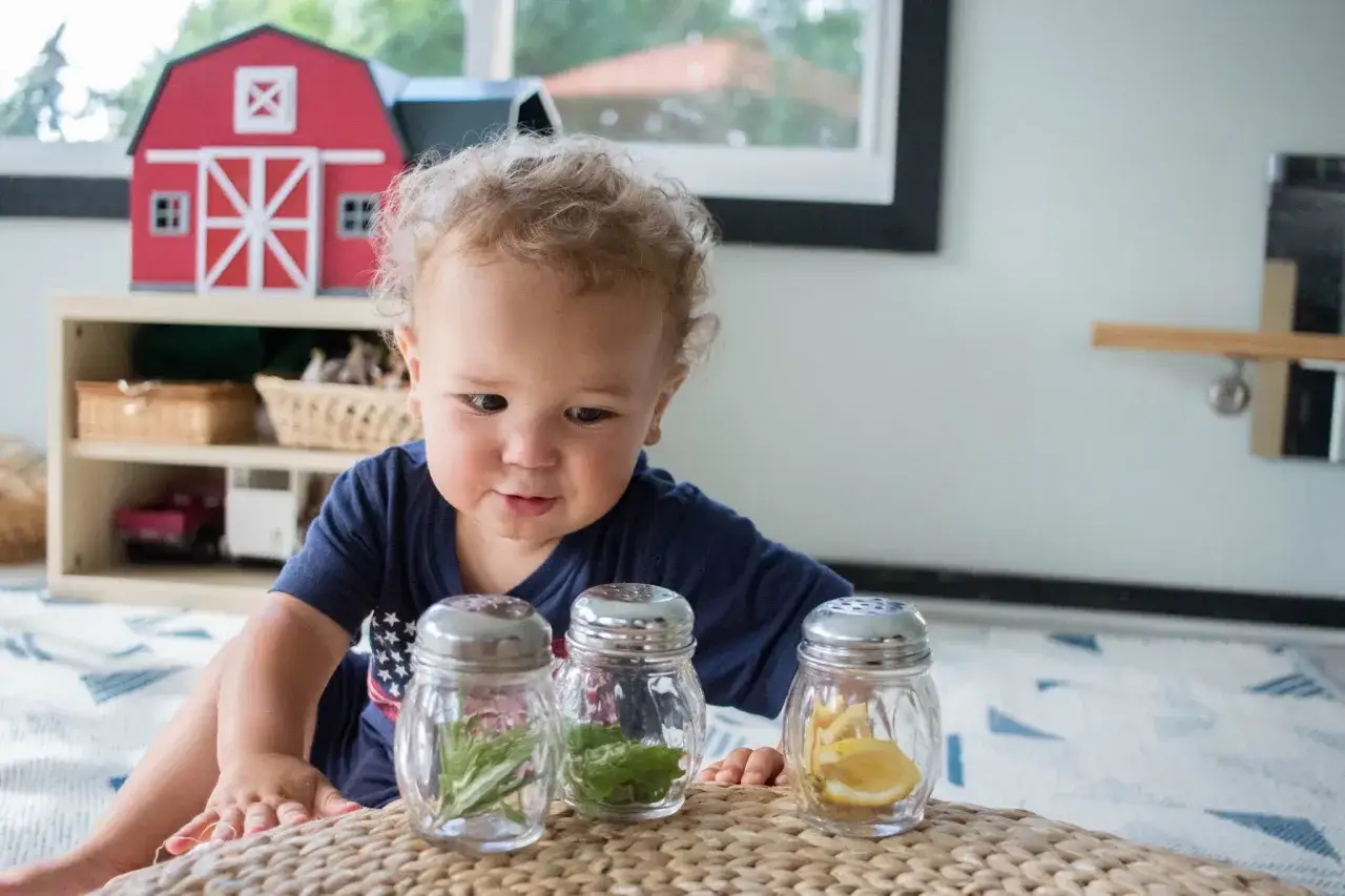 Curious baby explores Montessori activities for 10 month old baby: sensory jars with herbs and lemon.