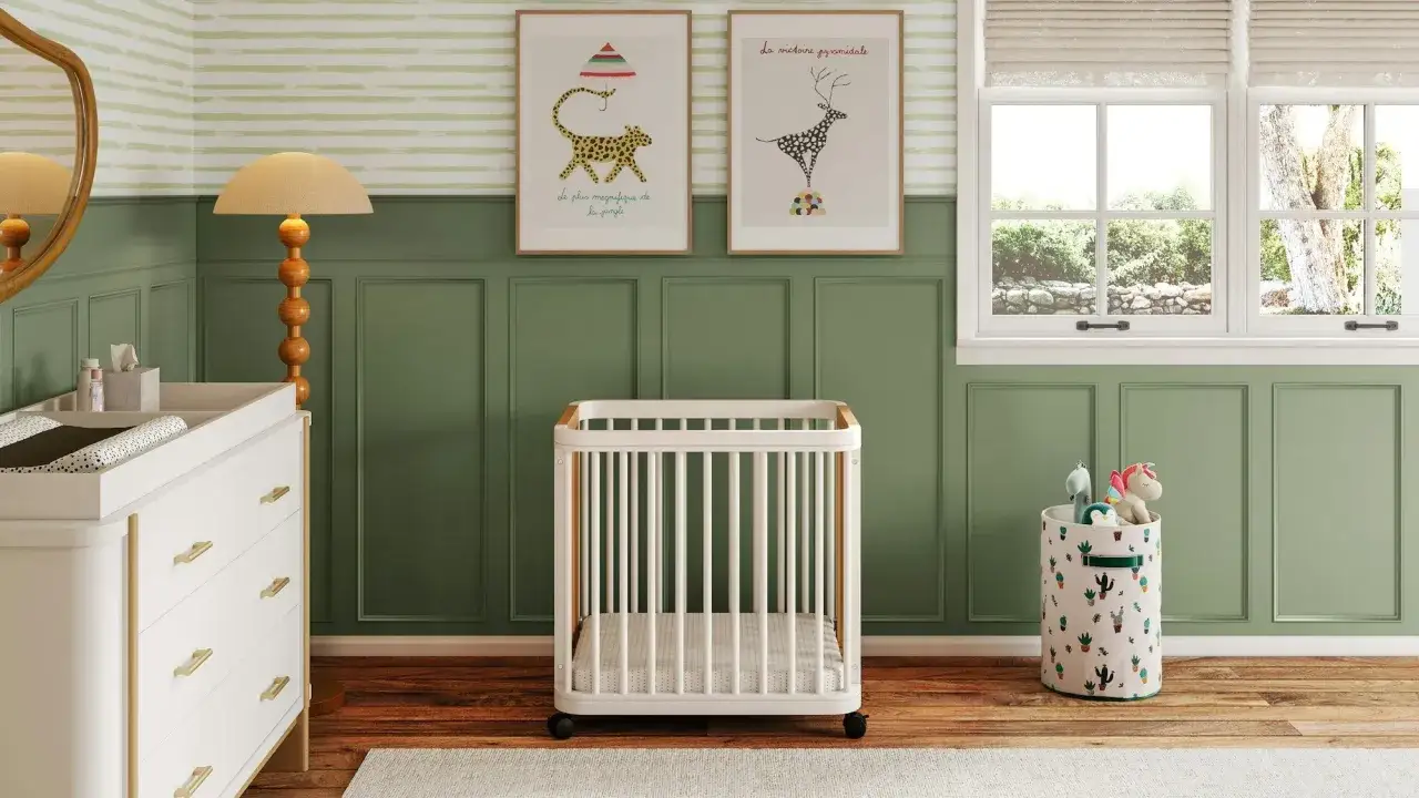 A serene nursery room, perfect for inspiration on how to paint a nursery room. Green wainscoting and striped wallpaper create a calming backdrop for a white crib and changing table.