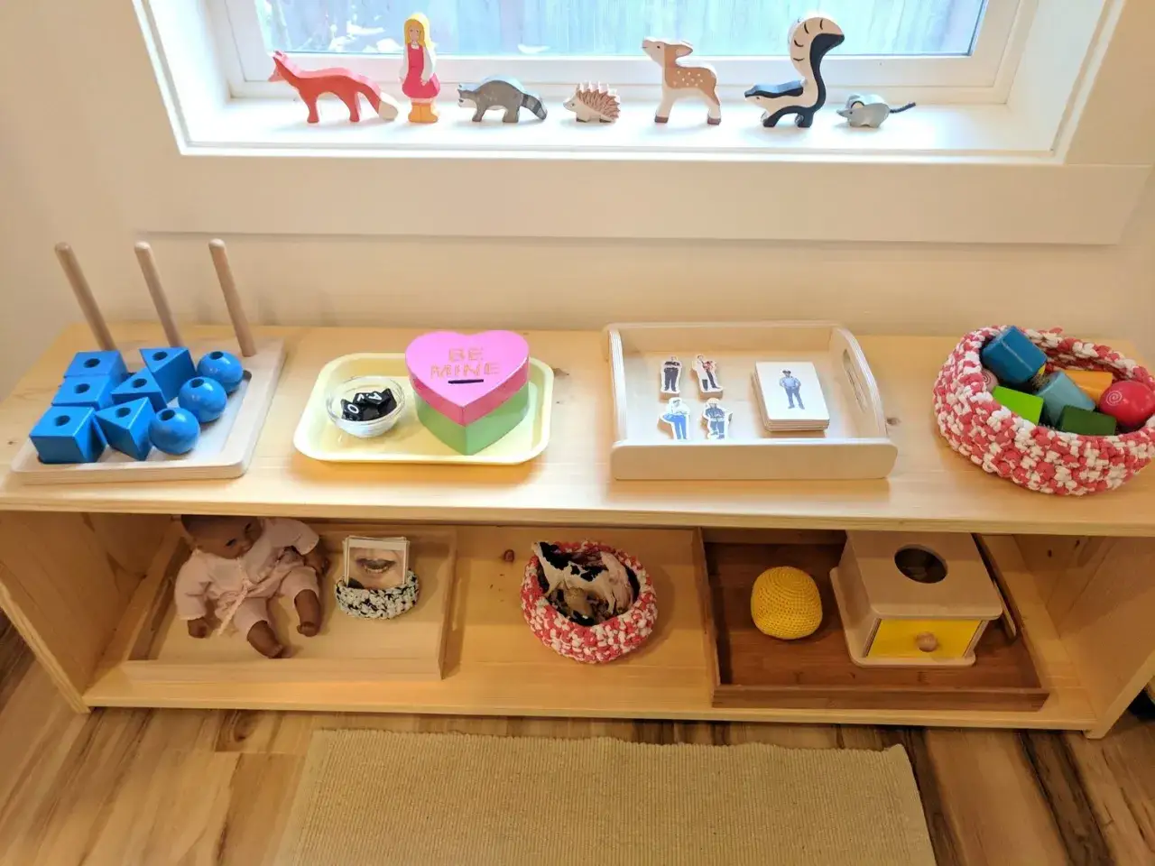 Montessori activities for 18 month old: wooden toys, shape sorter, doll, and a basket of blocks.