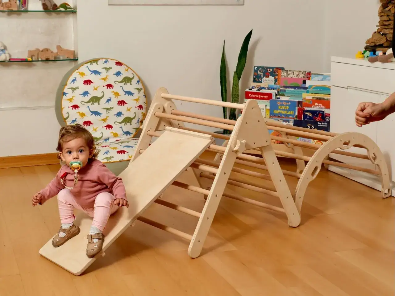 A baby sits on a slide of a wooden DIY Montessori playground.