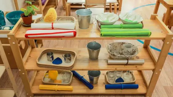 Montessori ideas: Shelves with practical life activities like pouring, washing, and transferring. Includes buckets, bowls, cups, and sponges.