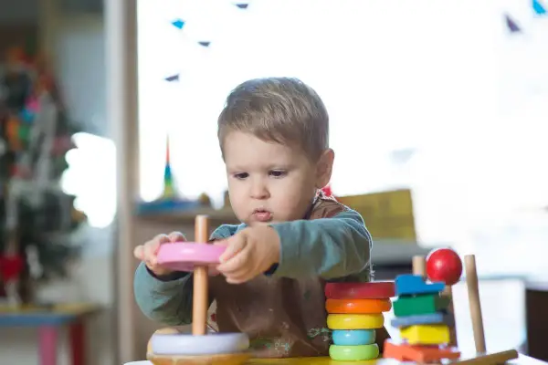 A toddler explores stacking toys, demonstrating early understanding of Montessori schemas.